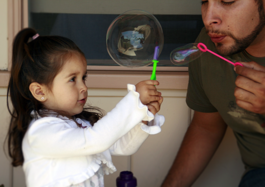 Little girl blowing bubbles with uncle